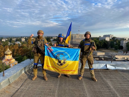 우크라이나 군인들이 국토를 회복한 쿠피안스크의 한 건물 옥상에서 깃발을 들고 있다. 사진=로이터
