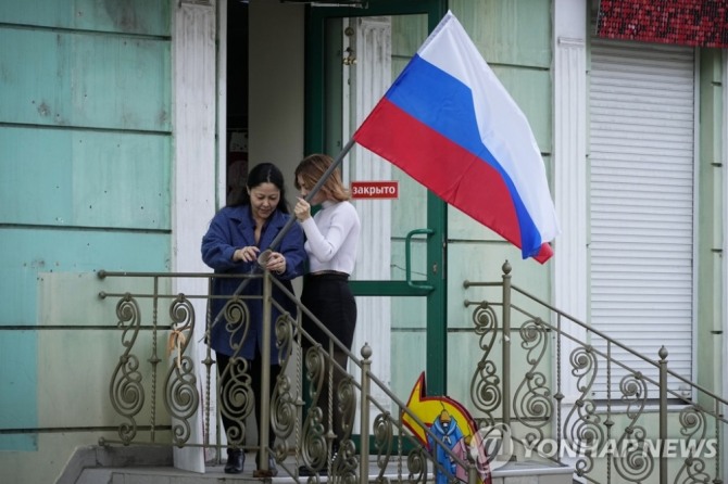 28일(현지시간) 러시아 귀속 주민투표가 끝난 우크라이나 루한스크에서 한 시민이 자신의 가게에 러시아 국기를 게양하고 있다. [사진=로이터]