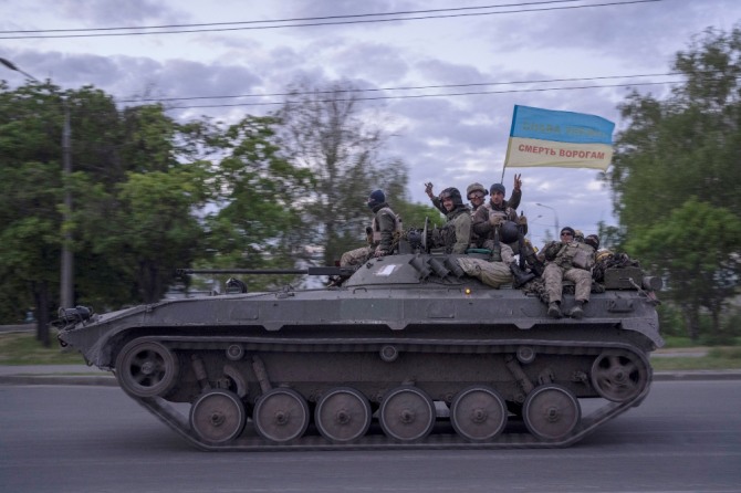 우크라이나 군인들이 우크라이나에 영광을 적에게 죽음을이라고 쓰인 깃발을 단 전차에 올라 손을 흔들며 도로를 지나고 있다. 사진=뉴시스