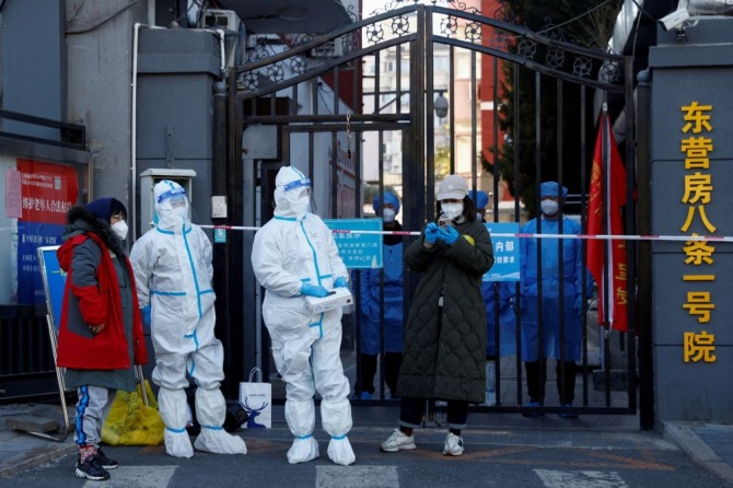 방역복을 입고 있는 의료진들이 베이징의 아파트 단지 출입구 앞에 서 있다. 사진=로이터