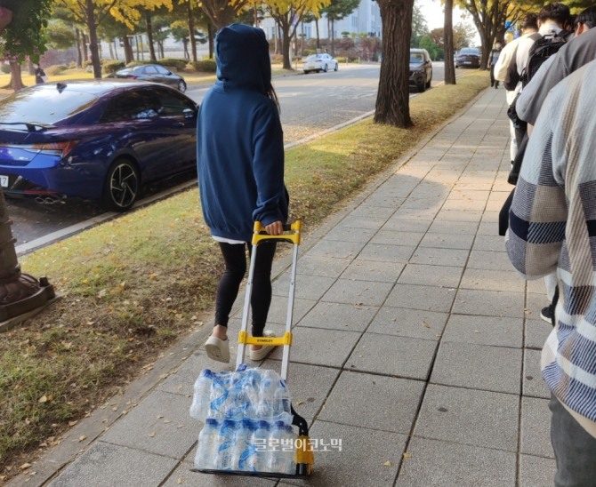 서울 국회의사당 앞에서 열린 '게임물관리위원회(게임위) 비위 의혹 진상 규명을 위한 감사원 국민 청고 연대 서명' 캠페인에 시민들이 줄지어 선 가운데 한 시민이 생수를 싣고 다니며 나눠주고 있다. 사진=이원용 기자