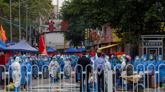 지난 5일 중국 광둥(廣東)성 광저우(廣州)의 고위험 지역에서 흰색 방호복을 입은 법 집행 요원들이 파란색 보호복을 입은 주민들을 이송할 준비를 하고 있다. 사진=뉴시스