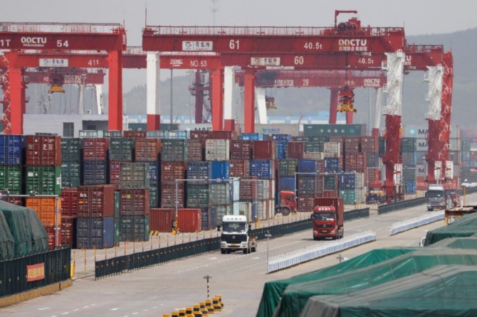 중국 산둥성 칭다오 항만에서 쌓여 있는 컨테이너들 옆으로 트럭들이 지나가고 있다.    사진=로이터