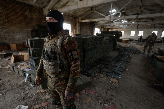 우크라이나의 한 군인이 헤르손에서 노획한 러시아 탄약 옆에 서 있다. 사진=로이터