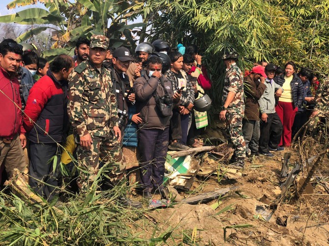 현지인들이 15일(현지시간) 네팔 포카라에서 여객기 잔해를 지켜보고 있다. 네팔 포카라 국제공항 인근에서 72명이 탑승한 여객기가 추락했다.