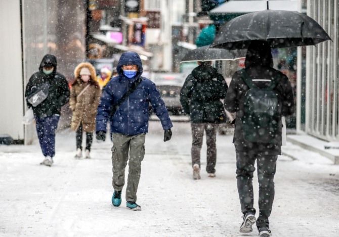서울을 포함한 수도권에 눈이 내린 지난 26일 오전 서울 중구 명동에서 시민들이 눈을 맞으며 이동하고 있다. 사진=뉴시스