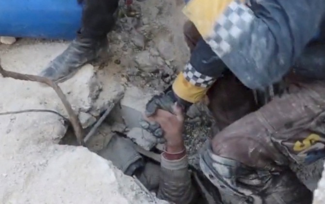 지진으로 무너진 시리아 북서부 알레포주 잔다리스의 건물 잔해에 파묻힌 한 소년이 8일(현지시간) 팔을 뻗어 구조대원 손을 잡고 있다. 사진=로이터