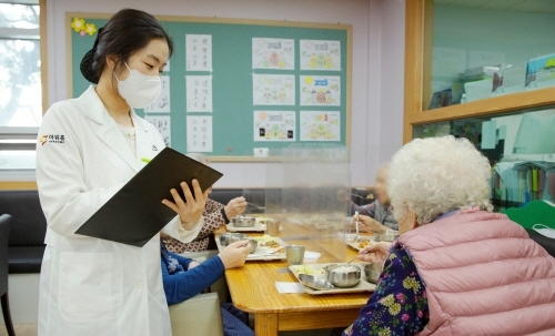 아워홈 영양사가 서울 마포구에 위치한 한서데이케어센터에서 시설 이용자에게 ‘인지기능개선 관리 식단’을 소개하고 있다. 사진=아워홈.