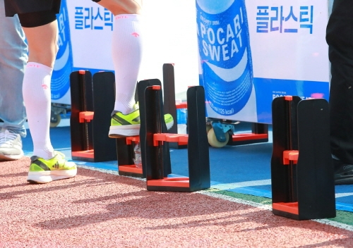 서울마라톤 참가자가 분리배출 방법 안내에 따라 페트병을 밟고 있다. 사진=동아오츠카.