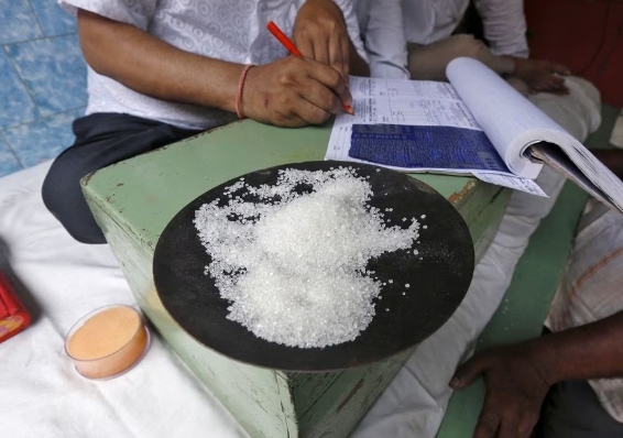 인도 시장에서 설탕 결정체 상품을 보고 있는 상인. 사진=로이터