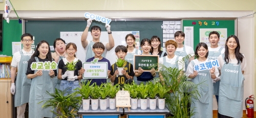 코웨이 임직원 봉사자들과 초등학생들이 '청정학교 교실숲 제4호' 조성 기념 단체 사진을 찍고 있다. 사진=코웨이.