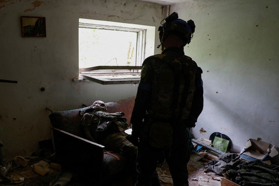 우크라이나 군인이 최근 탈환한 블라호다트네 마을 문화의 집 안에서 러시아 군인의 시신을 바라보고 있다.사진=로이터