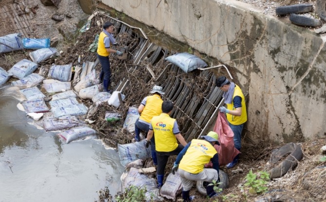 서부발전 직원들이 하천에 유실된 가축 사료 포대를 수거하고 있다.