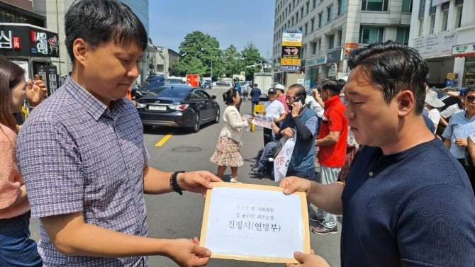 박윤희 청년 책임당원(오른쪽)이 국민의힘 사무처 직원에게 성명서와 연명부 전달하고 있다