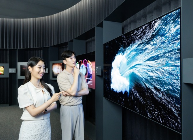 LG디스플레이 모델들이 점유율 1위를 차지한 대형 OLED 부문의 3세대 OLED TV 패널을 감상하고 있다. 사진=LG디스플레이