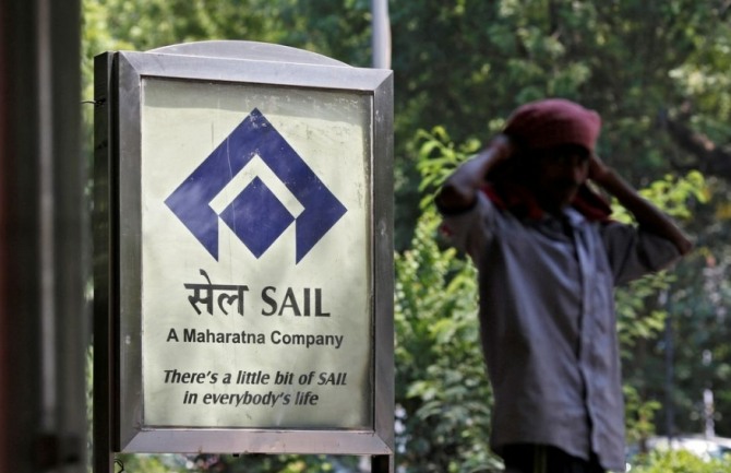 한 남자가 인도 뉴델리의 한 거리에서 SAIL(Steel Authority of India Ltd.)의 광고 옆에 서 있다.