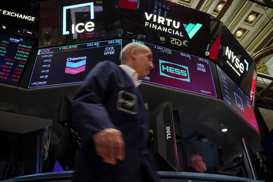 23일(현지시간) 미국 뉴욕증권거래소(NYSE)에서 셰브론과 헤스의 로고가 화면에 표시되는 동안 트레이더들이 트레이딩 플로어에서 일하는 모습. 사진=로이터