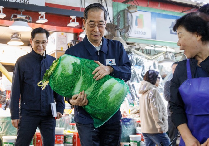 한덕수 국무총리가 24일 오후 농수산물 물가 점검을 위해 서울 마포구 마포농수산물시장을 찾아 직접 배추를 골라 구입하고 있다. 사진=연합뉴스