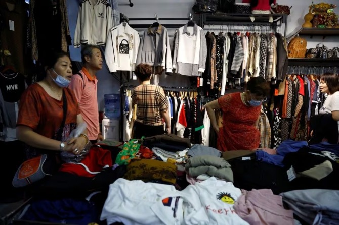 중국 베이징 도매시장 내 노점에서 고객이 옷을 쇼핑하고 있다. 사진=로이터