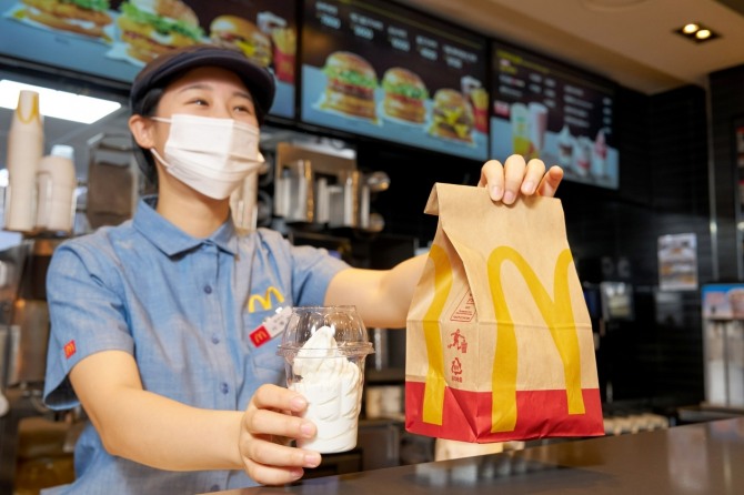 한국맥도날드 매장 직원이 친환경 재생페트(rPET) 컵에 담긴 '선데이 아이스크림'을 고객에게 건네는 모습. 사진=한국맥도날드 