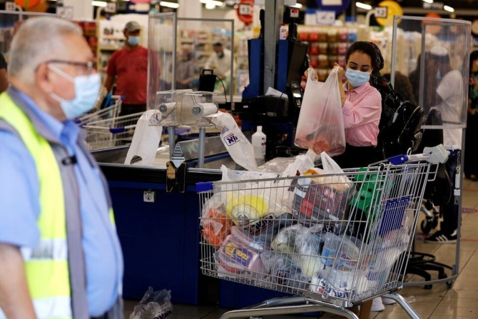 이스라엘 아슈도드에서 한 여성이 슈퍼마켓 계산대에서 물건을 정리하고 있다. 사진=로이터 
