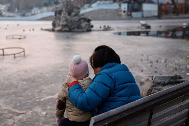 한 중국 여성이 아이를 데리고 수도 베이징에 있는 한 공원에 산책을 나와 아이를 돌보고 있다. 사진=로이터