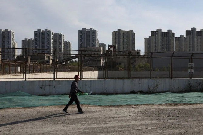 한 남자가 중국 베이징의 주거용 건물 근처 건설 현장을 지나가고 있다. 사진=로이터