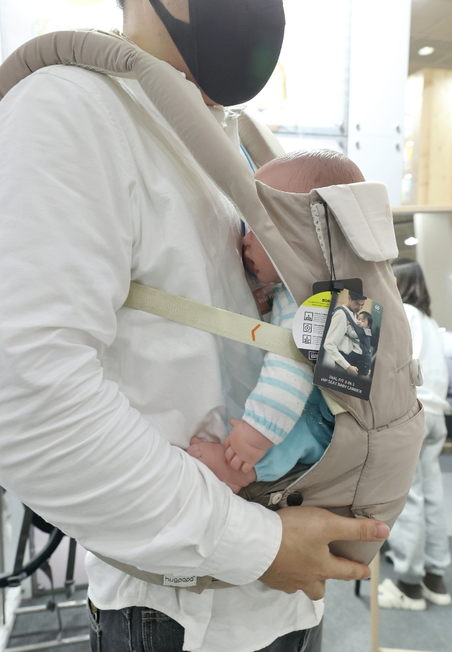 지난 15일 서울 강남구 코엑스에서 열린 '제45회 베페 베이비페어'에서 한 예비 아빠가 아기 띠를 체험하고 있다. 사진=연합뉴스