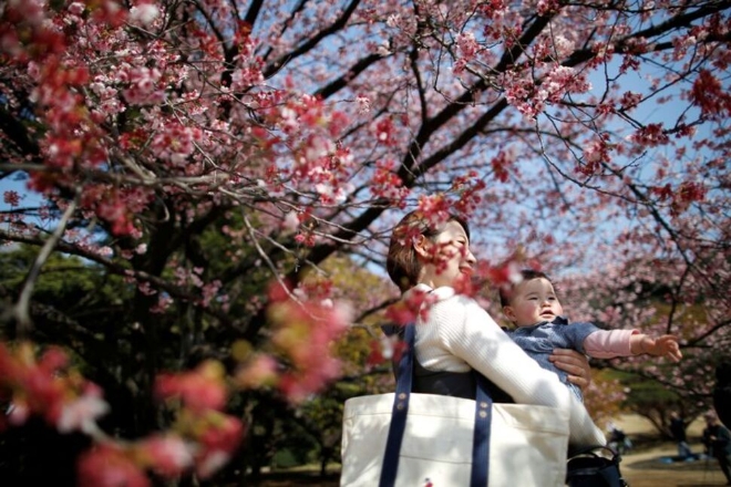 일본의 한 여성이 지난 2018년 3월 14일(현지시간) 수도 도쿄에 있는 신주쿠 교엔 국립정원에서 신생아와 함께 산책하고 있다. 사진=로이터