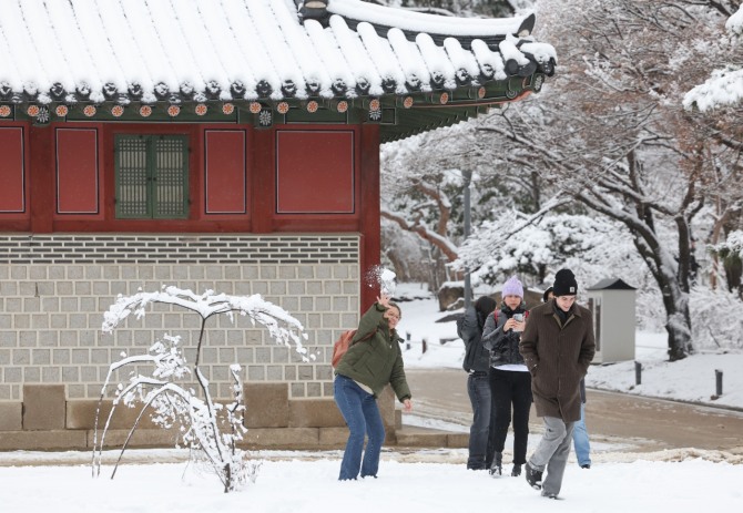  지난 22일 오전 밤사이 내린 눈이 쌓인 서울 덕수궁에서 외국인 관광객들이 눈싸움하고 있다. 사진=연합뉴스
