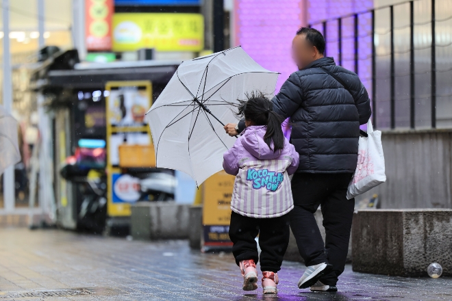 지난달 서울 중구 명동거리에서 한 어린이의 우산을 아빠가 잡아주고 있다. 사진=연합뉴스