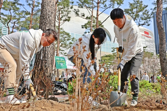 롯데물산 임직원들이 재활용 원사로 만든 친환경 단체복을 입고 나무를 심고 있다. / 사진=롯데물산
