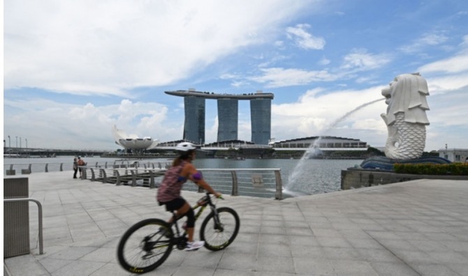 2021년 8월 11일, 싱가포르 마리나 베이의 마리온 파크에서 자전거를 타고 사람이 지나가고 있다. 사진=신화/뉴시스