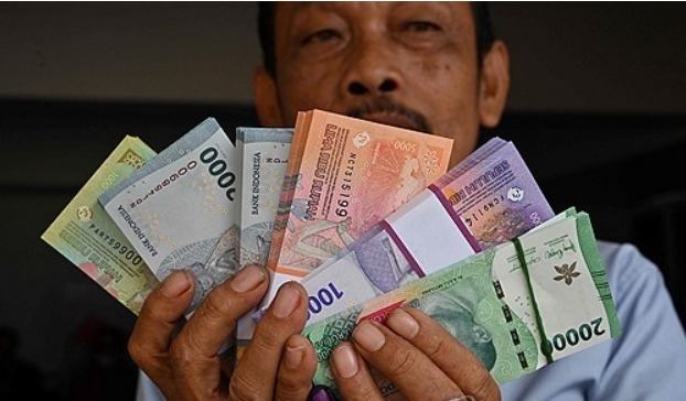 2024년 3월28일 자카르타에서 한 남성이 루피아 화폐를 보여주고 있다.     사진=AFP/연합뉴스