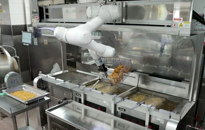 두산로보틱스 협동로봇이 춘천한샘고등학교 급식식당 주방에서 단체급식 튀김작업을 수행하고 있다. 사진=두산로보틱스