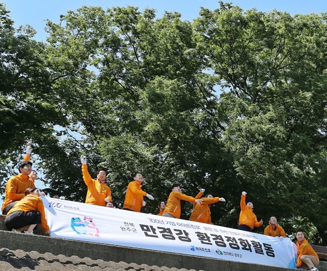 하이트진로는 지난 13일 전북 완주군 만경강에서 김인규 하이트진로 대표(앞줄 왼쪽 두번째), 유희태 완주군 군수(앞줄 왼쪽 첫번째) 등 임직원들이 참석한 가운데 만경강 환경정화활동을 진행했다. / 사진=하이트진로