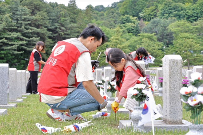 샤롯데 봉사단이 묘비 옆에 태극기를 꽂고 있다.(사진 제공=롯데건설