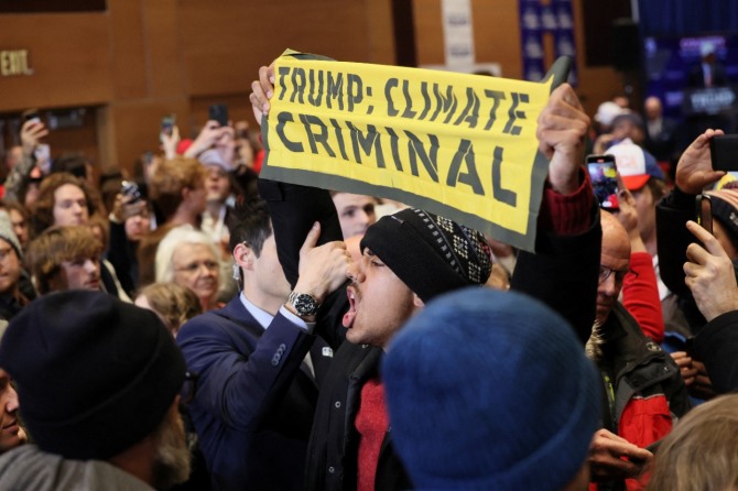 기후변화에 대해 부정적인 입장을 유지하고 있는 도널드 트럼프 미국 전 대통령에 반대하는 한 시위자가 최근 아이오와주 인디애나에서 열린 트럼프 후보의 선거운동 행사에서 트럼프는 기후 범죄자라고 쓰인 팻말을 들고 고함을 지르고 있다. 사진=로이터