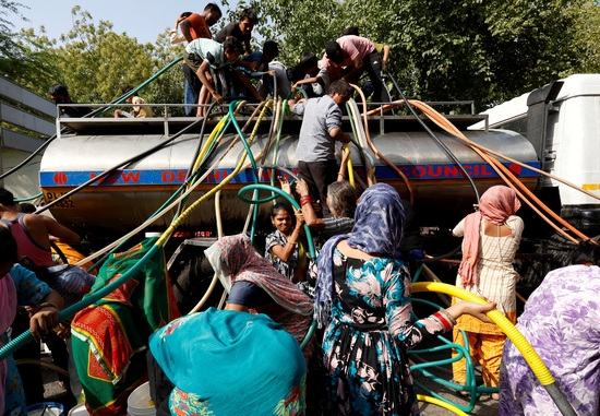 지난 13일 인도 뉴델리에서 주민들이 더운 날 물탱크에서 식수를 공급하기 위해 파이프를 사용하고 있다. 사진=로이터