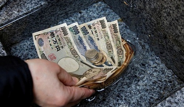 2017년 11월 13일 일본 도쿄 니혼바시 상업 지구에 있는 고아미 신사에서 한 방문객이 일본 엔화 지폐와 동전을 물에 씻고 번영을 기원하고 있다. 사진=로이터/연합뉴스
