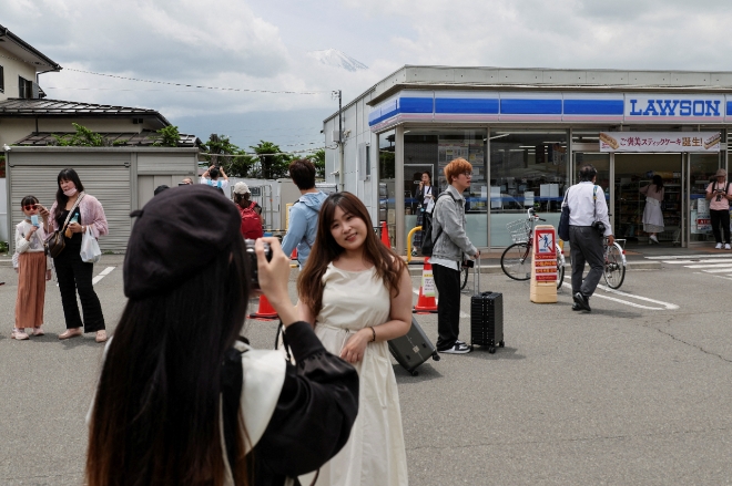 과잉 관광 문제로 골치를 앓고 있는 일본의 대표 관광명소 ‘후지산’에 오르기 전에 기념촬영을 하는 관광객들. 사진=로이터