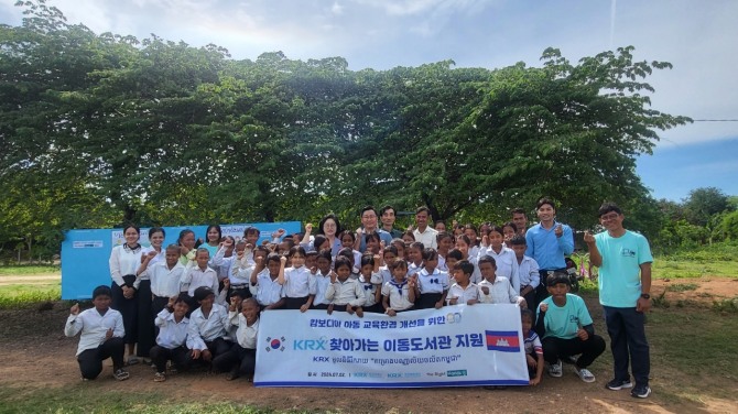 황우경 KRX국민행복재단 사무국장(가운데 좌측), 손정배 더라이트핸즈 대표(가운데 우측)가 캄보디아 오우다 초등학교 교사 및 학생들과 기념촬영을 하고 있다. 사진=한국거래소