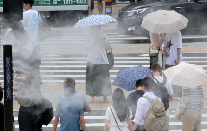 부산지역에 폭염주의보가 발효 중인 지난 22일 동구 부산역 앞에서 시민들이 쿨링포그가 작동하는 횡단보도를 건너고 있다. 사진=로이터