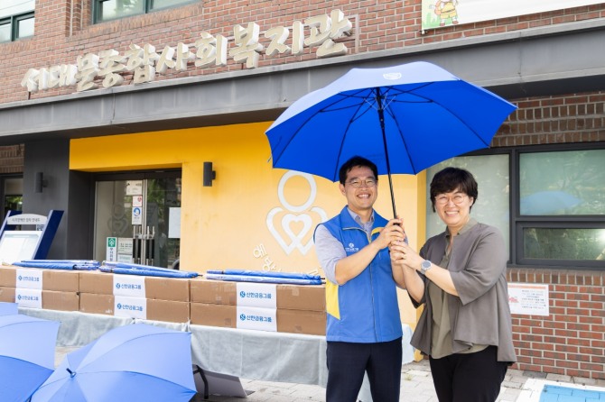 신한금융그룹은 지난 2일 서울 서대문구 종합사회복지관에 최근 잇따른 폭염과 국지성 호우 대비를 위해 우산 200개를 전달했다고 밝혔다. 이날 김동진 신한지주 사회공헌팀 부부장(사진 왼쪽), 정미령 서대문종합사회복지관장이 기념촬영을 하고 있다. 사진=신한금융그