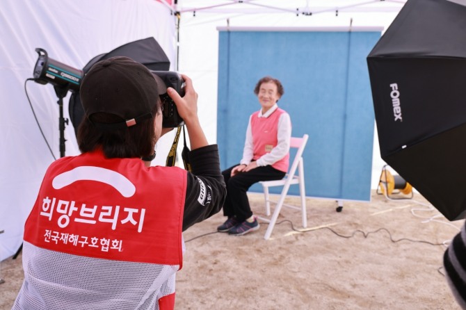 2024 괴산군 재난피해세대 지속돌봄사업 참여 대상자가 장수사진 촬영을 하고 있다. /사진=희망브리지