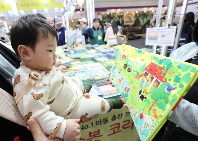 정부가 내년부터 '공무원 아빠'들 출산휴가 기간을 10일에서 20일로 2배 늘리기로 했다. 사진은 한 아기가 그림책을 보는 모습. 사진=연합뉴스 