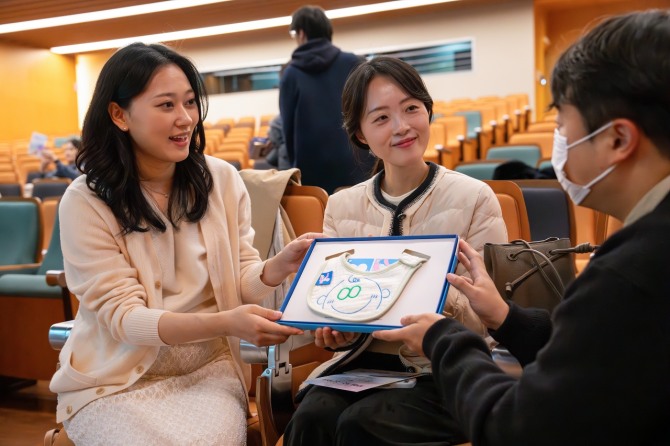 지난 22일 오후 광화문 교보생명 본사 23층 대산홀에서 열린 ‘찾아가는 음악회’에 참석한 임산부들이 스마일 턱받이를 건네 받고 있다. 사진=교보생명