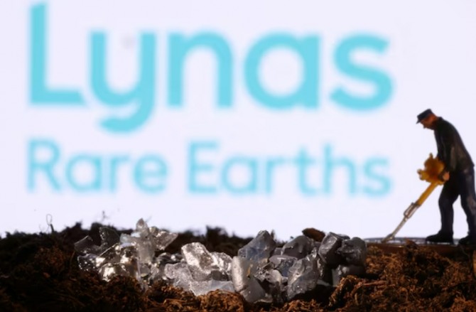 Lynas Rare Earths 로고 앞에 작은 장난감 피규어와 광물 모조품.  사진=로이터