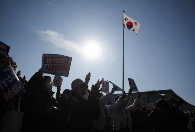 계엄령 선언을 비난하고 사임을 촉구하는 집회에 참석한 사람들이 플래카드를 들고 있다. 사진=로이터