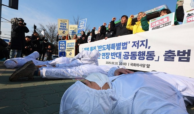 서울 여의도 국회 앞에서 10일 열린 '재벌 특혜 반도체특별법 저지 및 노동시간 연장 반대 공동행동 출범 기자회견'에서 방진복을 입은 참가자들이 과로로 쓰러지는 반도체 노동자를 형상화하는 퍼포먼스를 하고 있다. 사진=연합뉴스